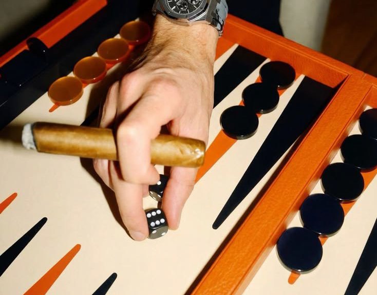A backgammon board in orange leather, a cigar in hand.